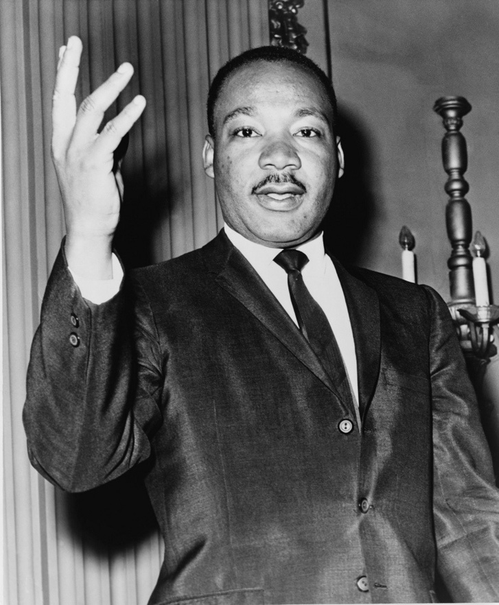  A Black-and-White Shot of Martin Luther King Jr. in a Suit Waving a Hand