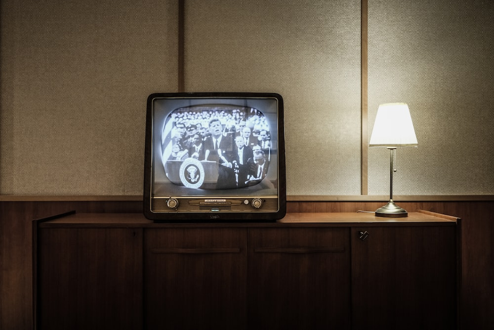 A Vintage Television Beside a Lamp Showing President John F. Kennedy Giving a Speech